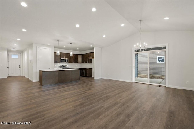 unfurnished living room with an inviting chandelier, dark hardwood / wood-style floors, and vaulted ceiling