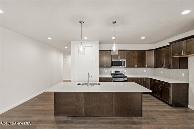 kitchen featuring dark wood-type flooring, sink, an island with sink, and stainless steel appliances