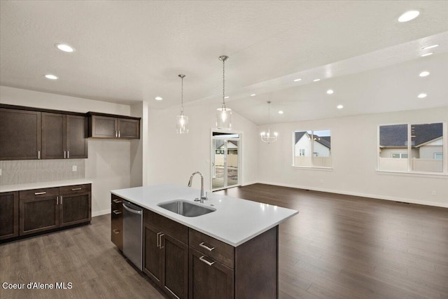 kitchen with hanging light fixtures, sink, dark wood-type flooring, and a center island with sink