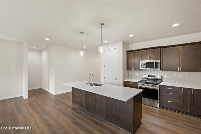 kitchen with a kitchen island with sink, pendant lighting, stainless steel appliances, and dark hardwood / wood-style floors