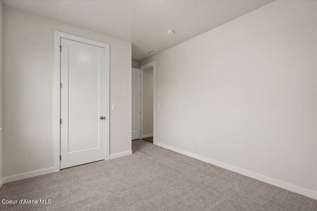 unfurnished bedroom with light colored carpet and a closet