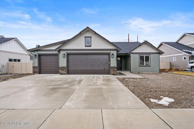 craftsman-style house featuring a garage, stone siding, and driveway