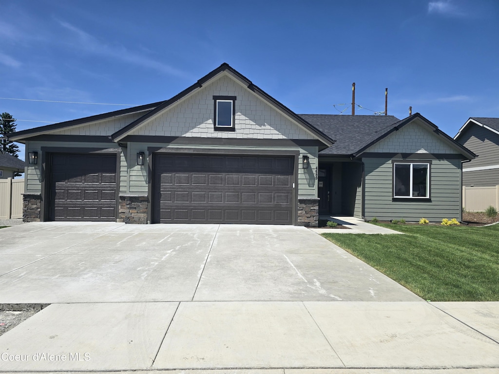 4689 W Homeward Bound Blvd, Coeur Dalene, ID 83815 - view of front of home featuring a garage, driveway, stone siding, and a front yard