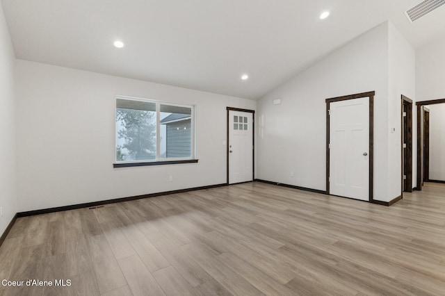 spare room featuring lofted ceiling and light wood-type flooring