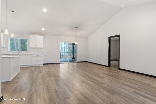 unfurnished living room featuring vaulted ceiling, light hardwood / wood-style flooring, and sink