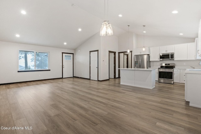 kitchen with a center island, white cabinets, hanging light fixtures, light wood-type flooring, and appliances with stainless steel finishes