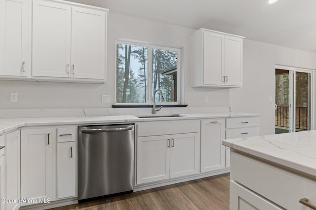 kitchen with white cabinetry, sink, stainless steel dishwasher, and hardwood / wood-style flooring