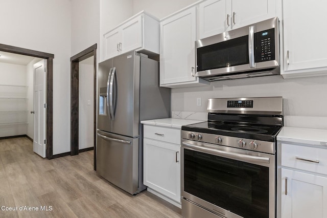 kitchen with light stone countertops, appliances with stainless steel finishes, light hardwood / wood-style flooring, and white cabinetry