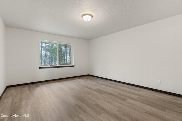 spare room with light hardwood / wood-style flooring and a textured ceiling