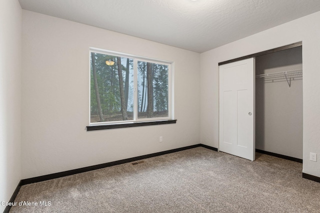 unfurnished bedroom with carpet flooring, a textured ceiling, and a closet