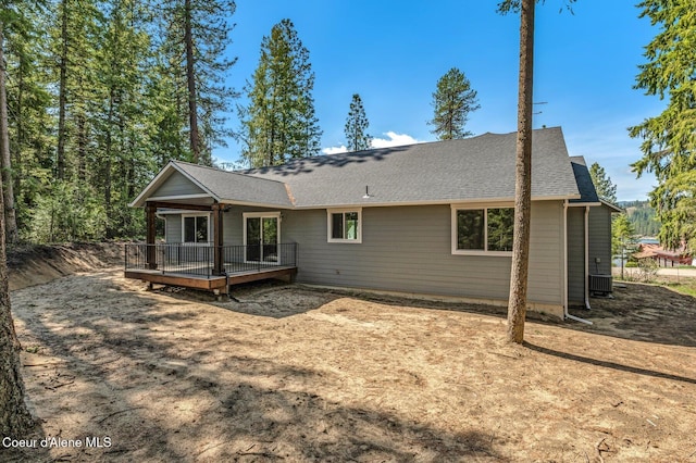 back of house featuring a shingled roof and a deck