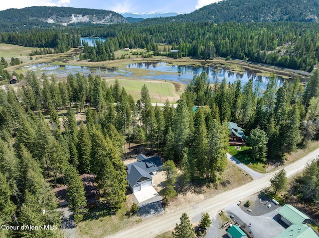 drone / aerial view with a water and mountain view and a forest view