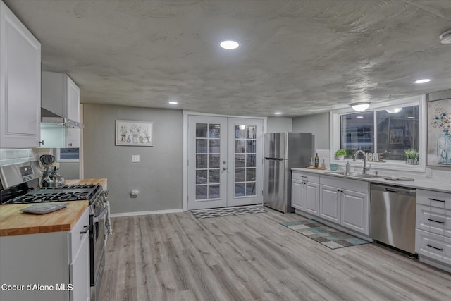 kitchen with french doors, white cabinetry, stainless steel appliances, and wooden counters