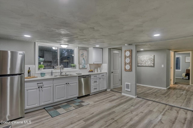 kitchen featuring white cabinets, stainless steel appliances, light hardwood / wood-style floors, and sink