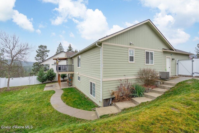 rear view of property with central AC, a wooden deck, and a lawn