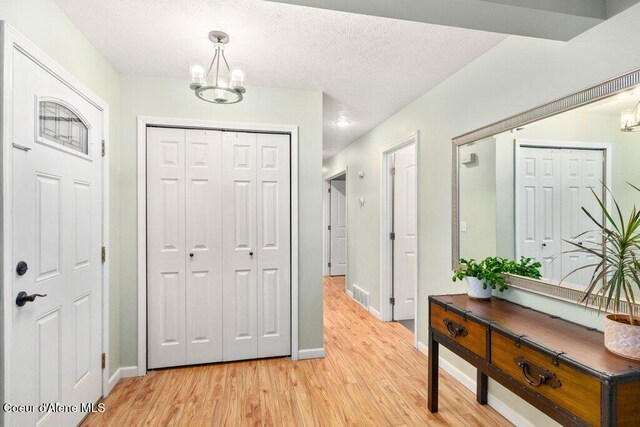 entrance foyer featuring light hardwood / wood-style floors, a textured ceiling, and a chandelier