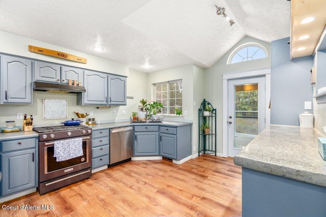 kitchen featuring a textured ceiling, stainless steel appliances, light hardwood / wood-style flooring, and lofted ceiling