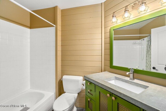 full bathroom with wood walls, vanity, tub / shower combination, and toilet