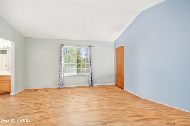 empty room with light hardwood / wood-style floors and vaulted ceiling