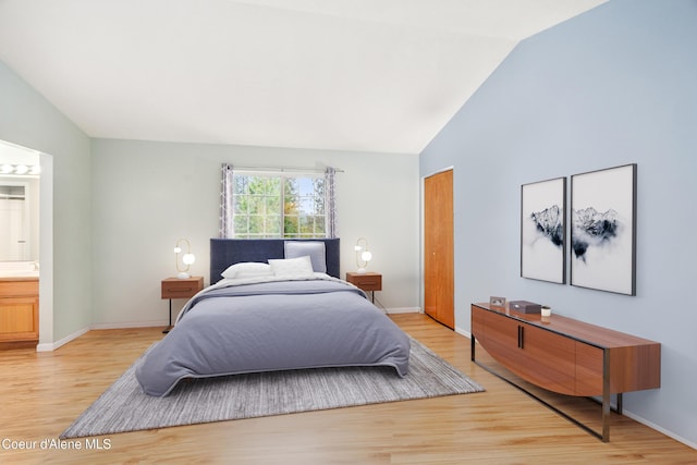 bedroom featuring light wood-type flooring, connected bathroom, and vaulted ceiling