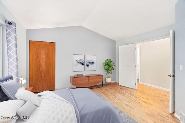 bedroom featuring hardwood / wood-style flooring, vaulted ceiling, and a closet