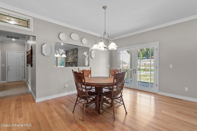 dining space with a chandelier, french doors, light hardwood / wood-style floors, and crown molding