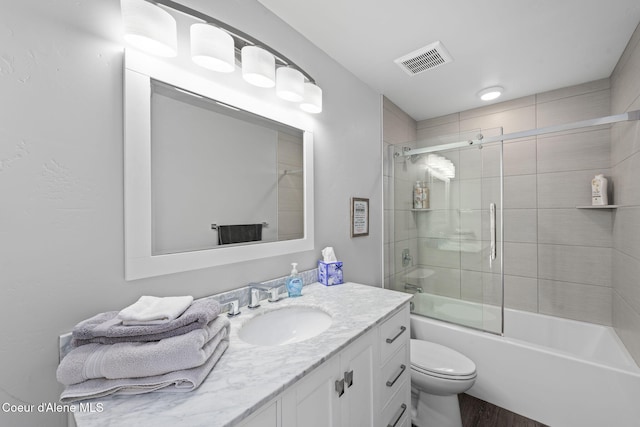 full bathroom with shower / bath combination with glass door, hardwood / wood-style floors, vanity, and toilet