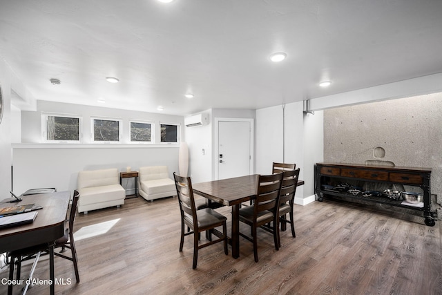 dining area with a wall mounted air conditioner and hardwood / wood-style flooring