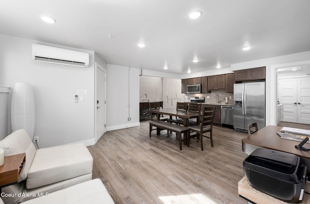 dining room featuring sink, a wall mounted air conditioner, and light wood-type flooring