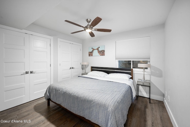 bedroom featuring two closets, dark hardwood / wood-style floors, and ceiling fan