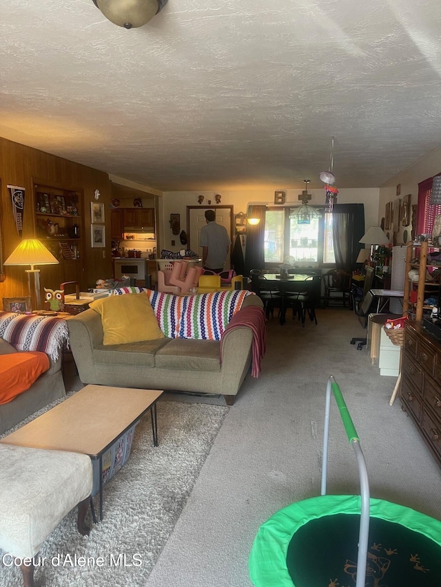 carpeted living room featuring a textured ceiling, vaulted ceiling, and wood walls