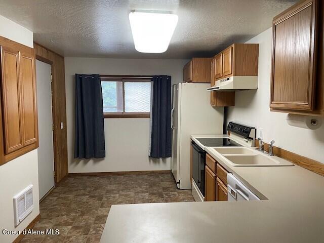 kitchen featuring a textured ceiling, stainless steel appliances, and sink