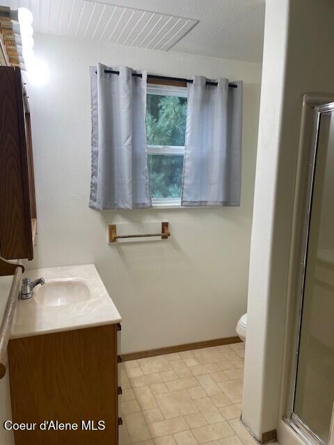 bathroom featuring vanity, toilet, and an enclosed shower