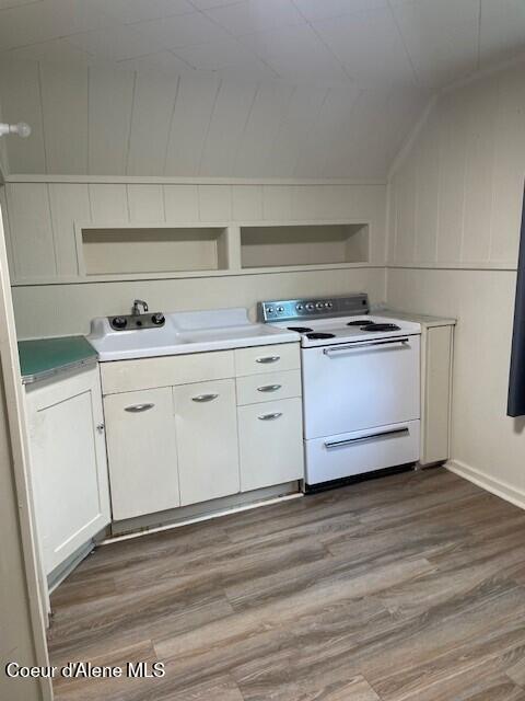 kitchen with white cabinets, wood-type flooring, electric range, and lofted ceiling