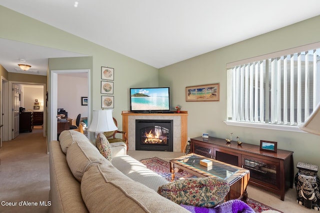 living room with light colored carpet, lofted ceiling, and a tiled fireplace