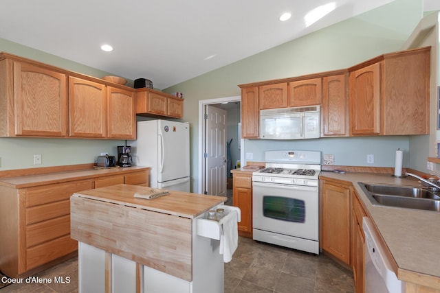 kitchen with white appliances, a kitchen island, lofted ceiling, and sink