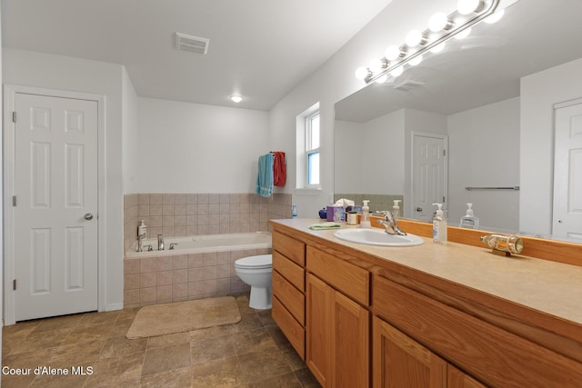 bathroom with vanity, toilet, and tiled tub