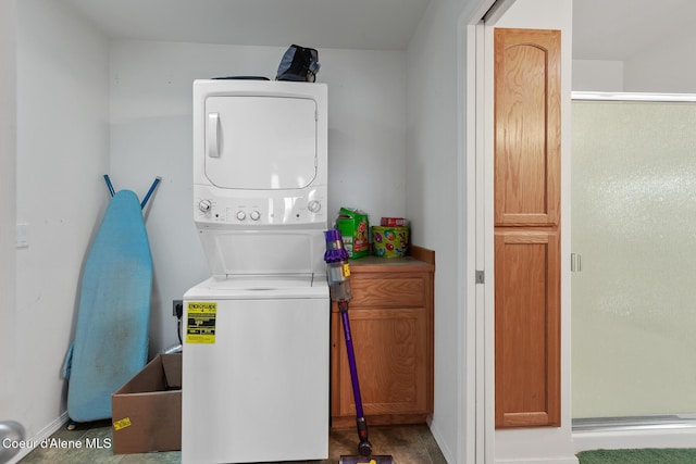 laundry area with stacked washing maching and dryer and hardwood / wood-style flooring