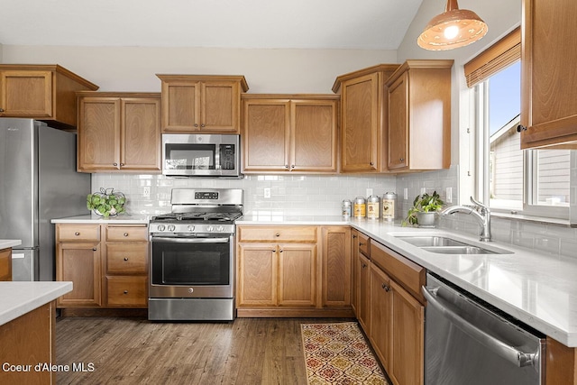 kitchen with hanging light fixtures, sink, decorative backsplash, appliances with stainless steel finishes, and dark hardwood / wood-style flooring