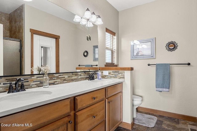 bathroom with tasteful backsplash, vanity, a shower with shower door, and toilet