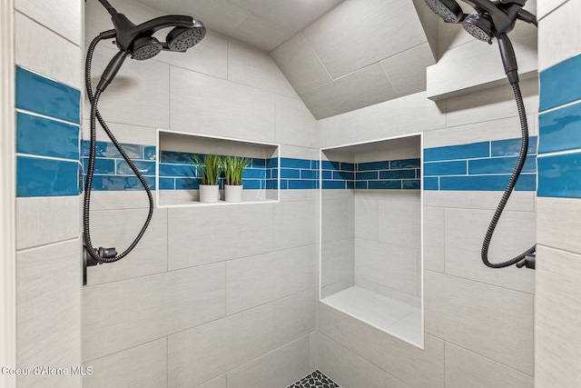 bathroom with a tile shower and lofted ceiling