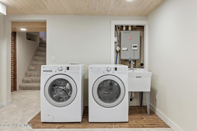 clothes washing area with independent washer and dryer, light hardwood / wood-style floors, and wooden ceiling