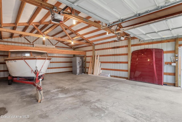 garage with stainless steel refrigerator with ice dispenser and a garage door opener