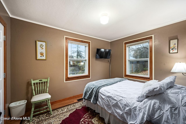 bedroom featuring multiple windows, crown molding, and hardwood / wood-style flooring