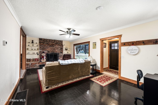 living room featuring crown molding, a brick fireplace, ceiling fan, a textured ceiling, and wood-type flooring