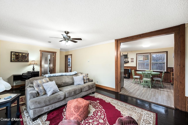 living room featuring hardwood / wood-style flooring, ceiling fan, crown molding, and a textured ceiling