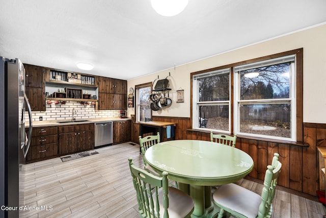 kitchen featuring decorative backsplash, appliances with stainless steel finishes, dark brown cabinetry, sink, and light hardwood / wood-style floors