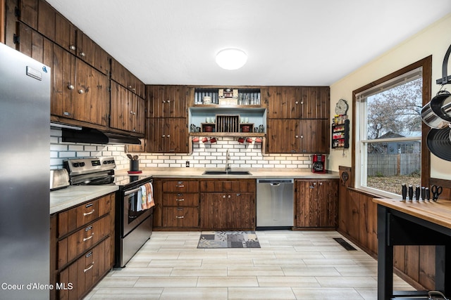 kitchen featuring dark brown cabinetry, sink, stainless steel appliances, tasteful backsplash, and light hardwood / wood-style floors