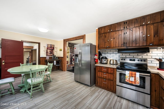 kitchen featuring appliances with stainless steel finishes, light wood-type flooring, and backsplash