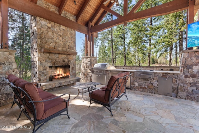 6126 S Gozzer Rd, Harrison, ID 83833 - view of patio featuring a grill, an outdoor stone fireplace, and an outdoor kitchen